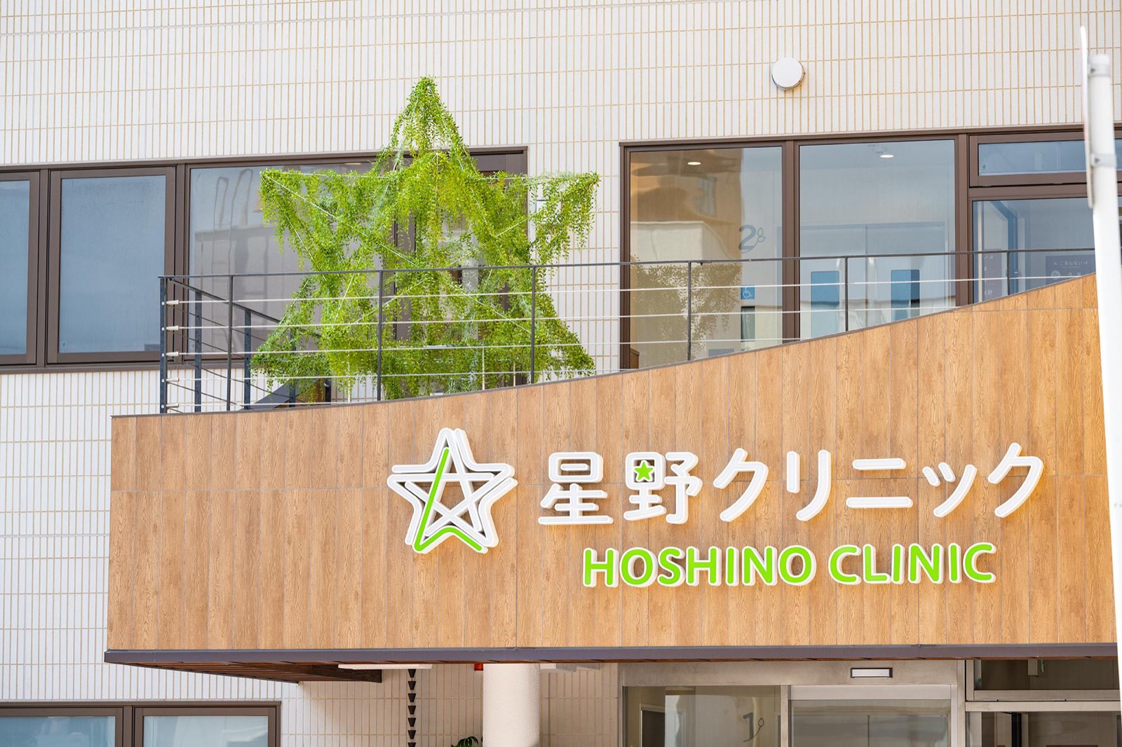 星野クリニックの外観。木目のサインに星のロゴと「星野クリニック HOSHINO CLINIC」の文字
